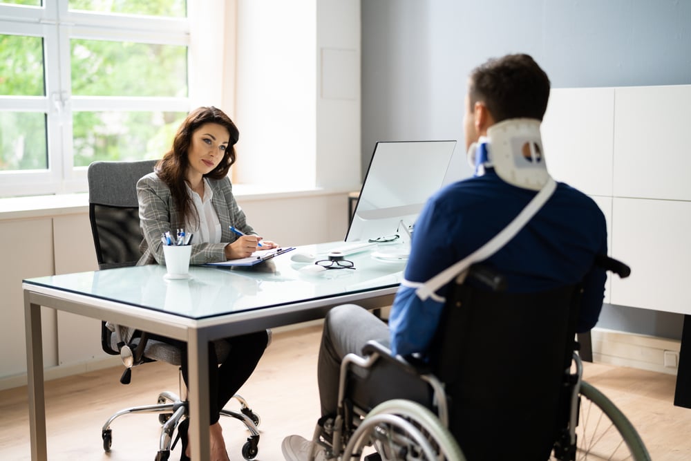 Injured man in wheelchair talking to a lawyer after a catastrophic accident