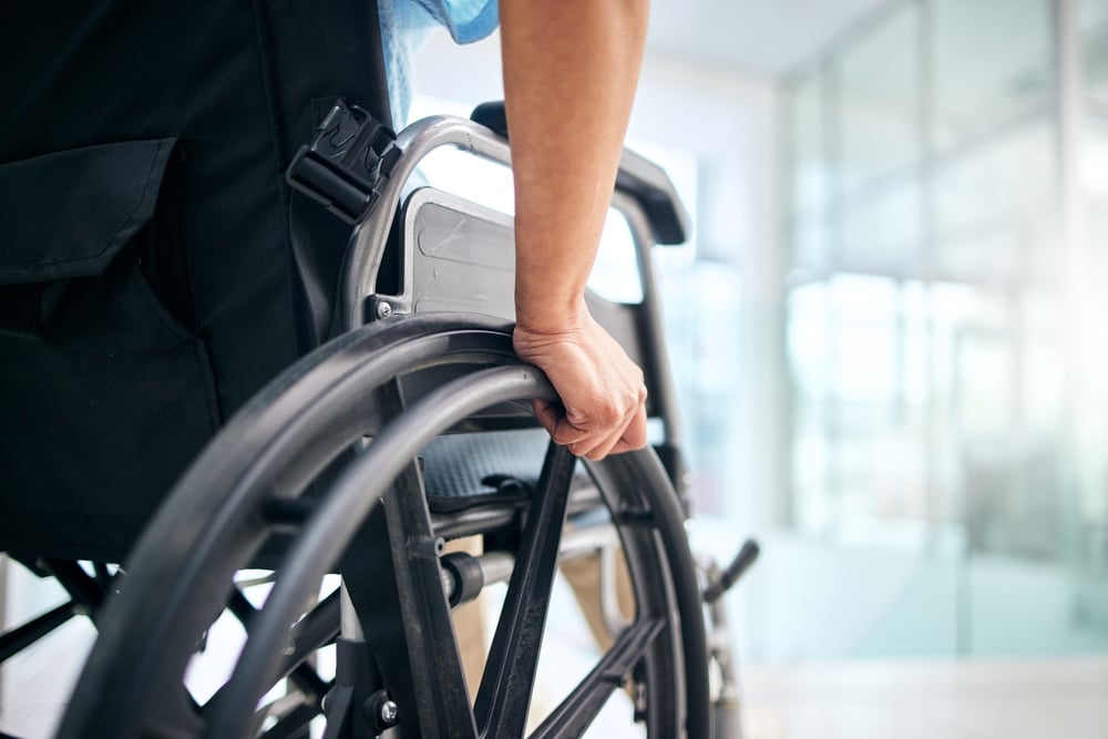 Closeup of mans arm holding a wheel of a wheelchair