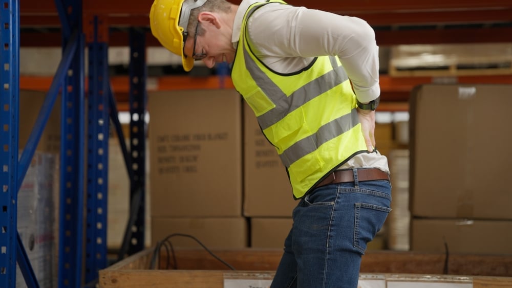 Warehouse employee holding his back after an injury at the workplace