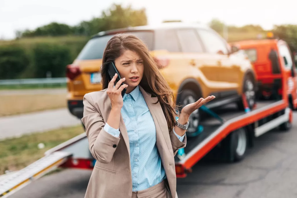 Elegant middle age business woman calling someone while towing service helping her on the road