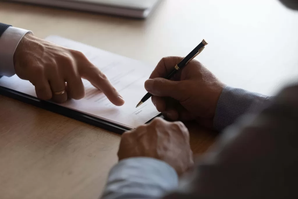 Hands of lawyer pointing at paper for businessman signing contract