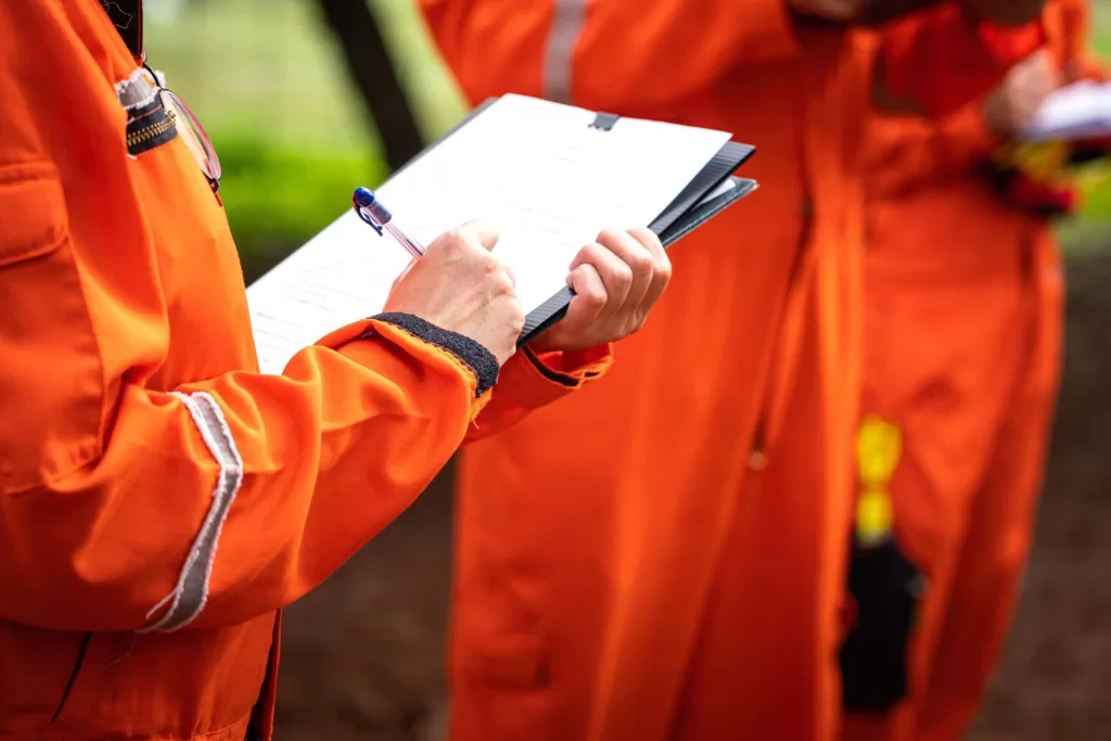 A safety supervisor or manager is writing down on paper