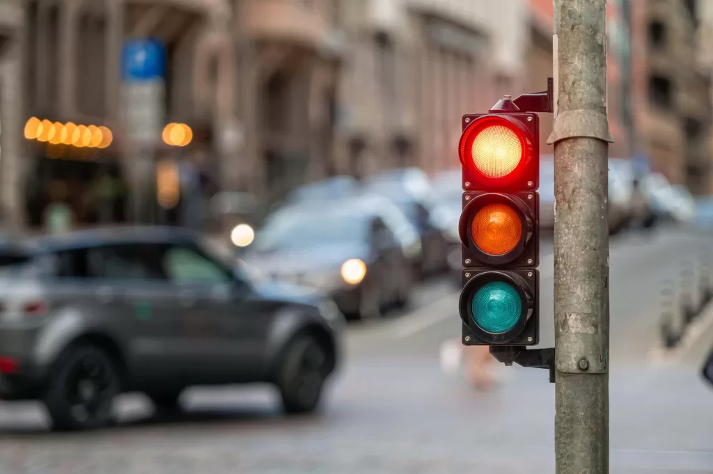 City crossing with a semaphore on blurred background with cars in the evening streets