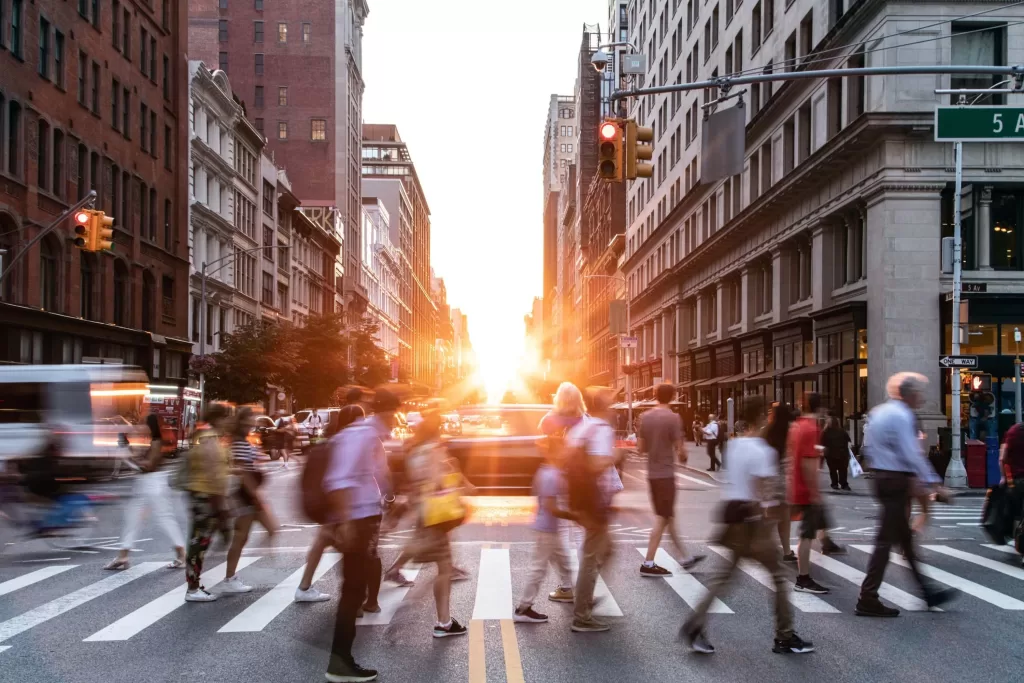 Diverse crowds of people walking through a busy intersection on 5th Avenue and 23rd Street in New York