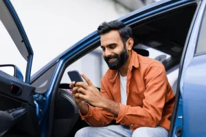 Happy middle Man Using Phone Sitting In Auto With Opened Door