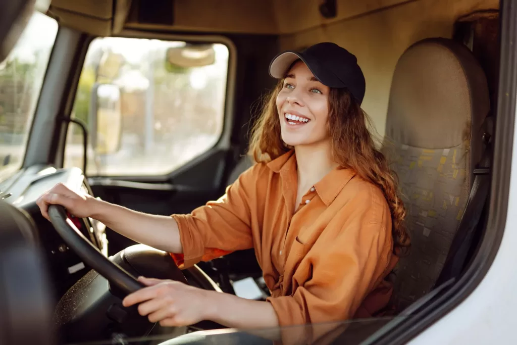 Young woman professional truck driver in a big truck