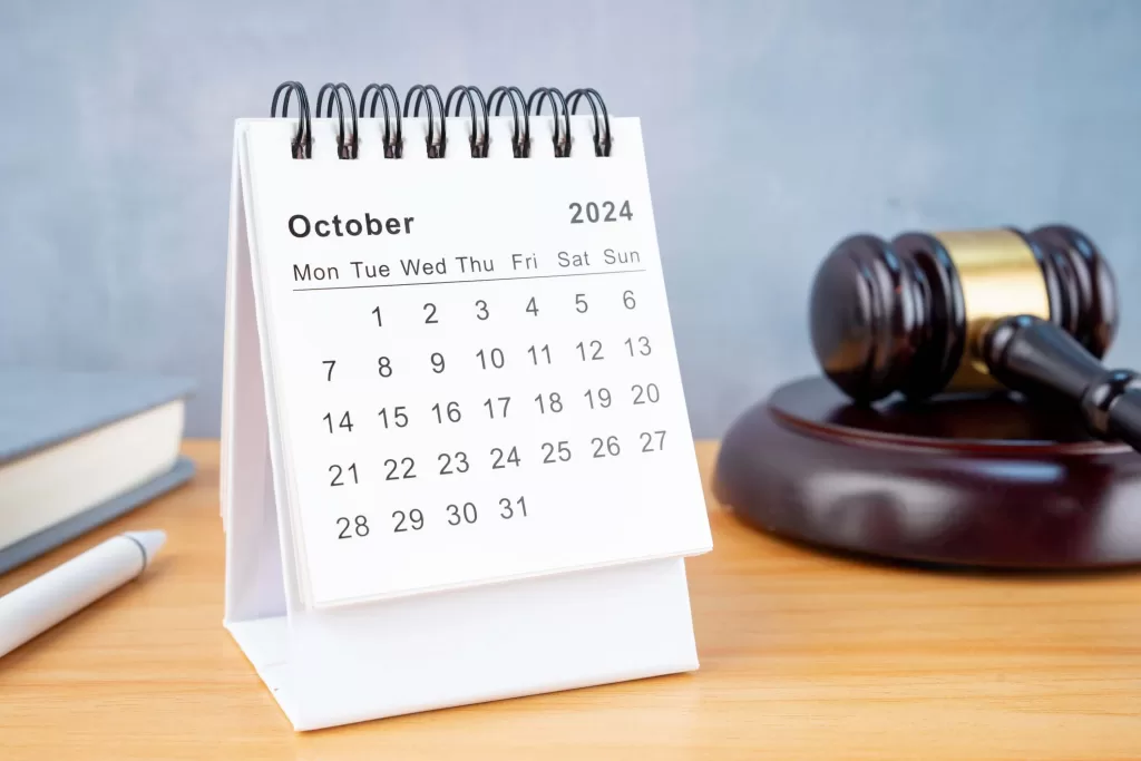 Desk calendar for October 2024 and judge's gavel on the worktable