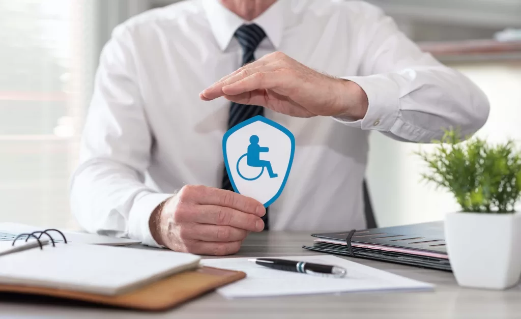 Concept of disability insurance with paper shield protected by hand of insurer