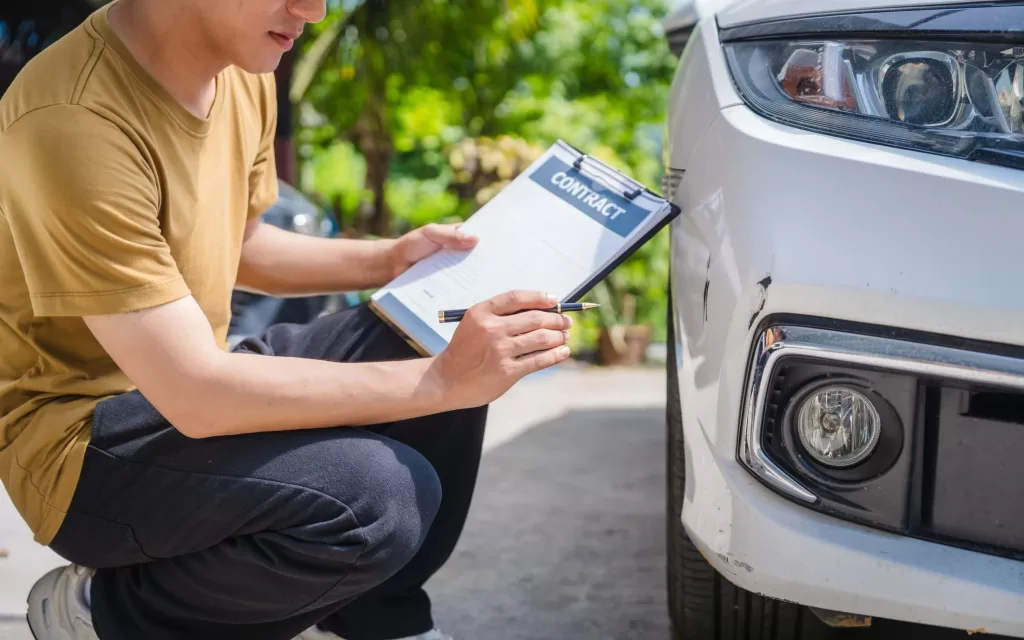 Man fills out a car insurance form after a car accident